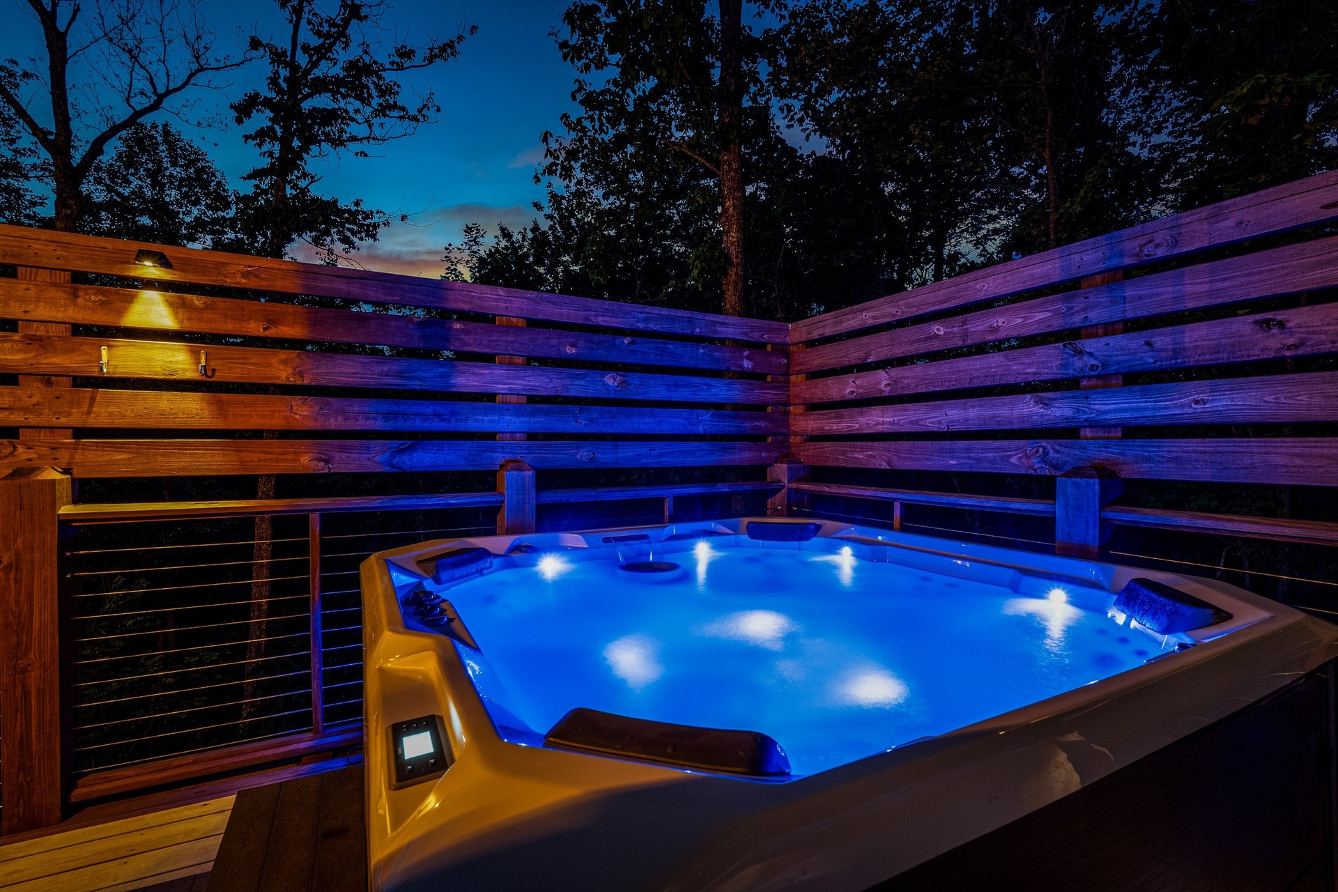 Private hot tub glowing blue under the night sky