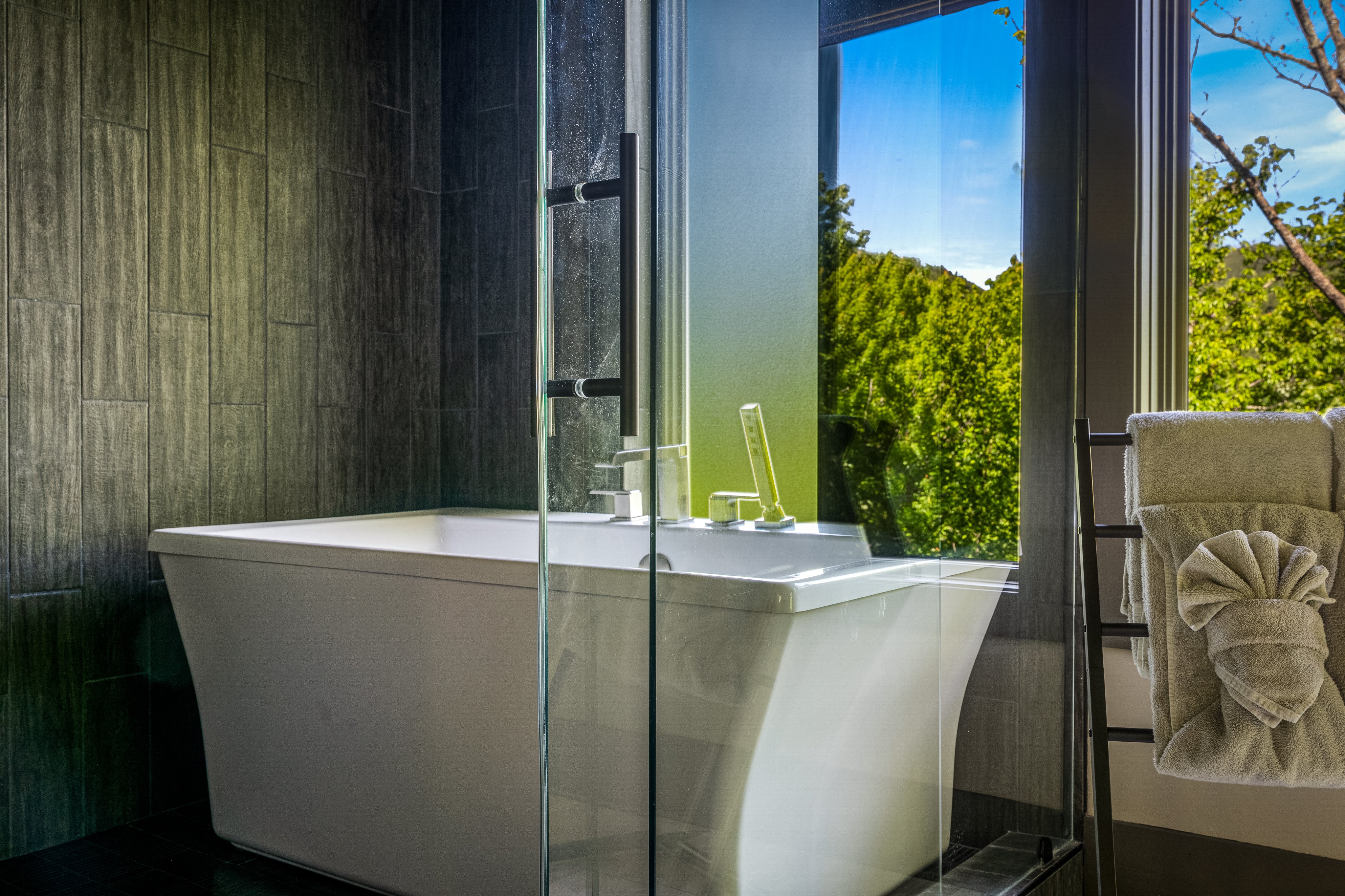 60-inch freestanding soaking tub by a forest-view window